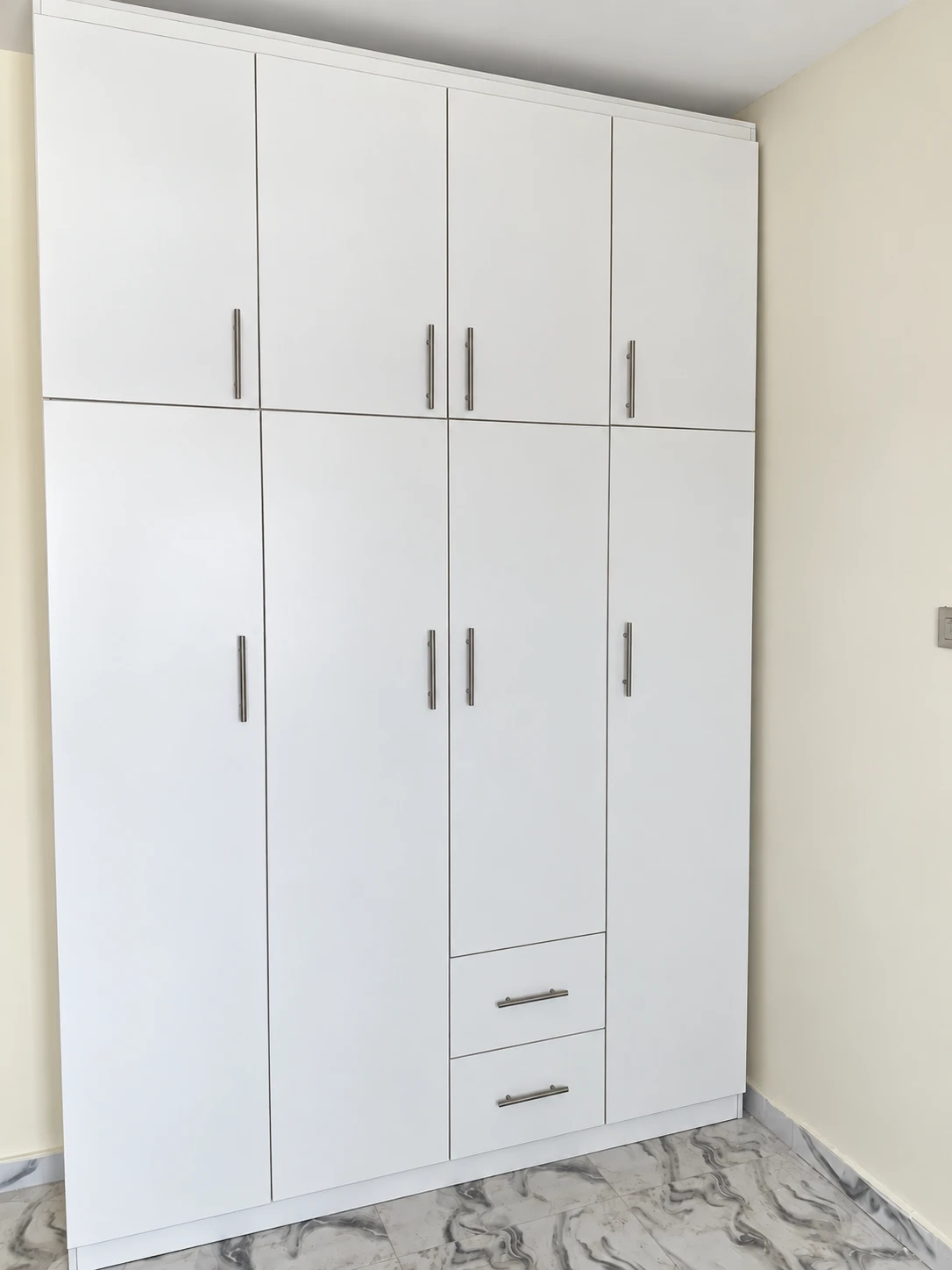 Tall white wardrobe with four top cabinets, four lower doors and two drawers