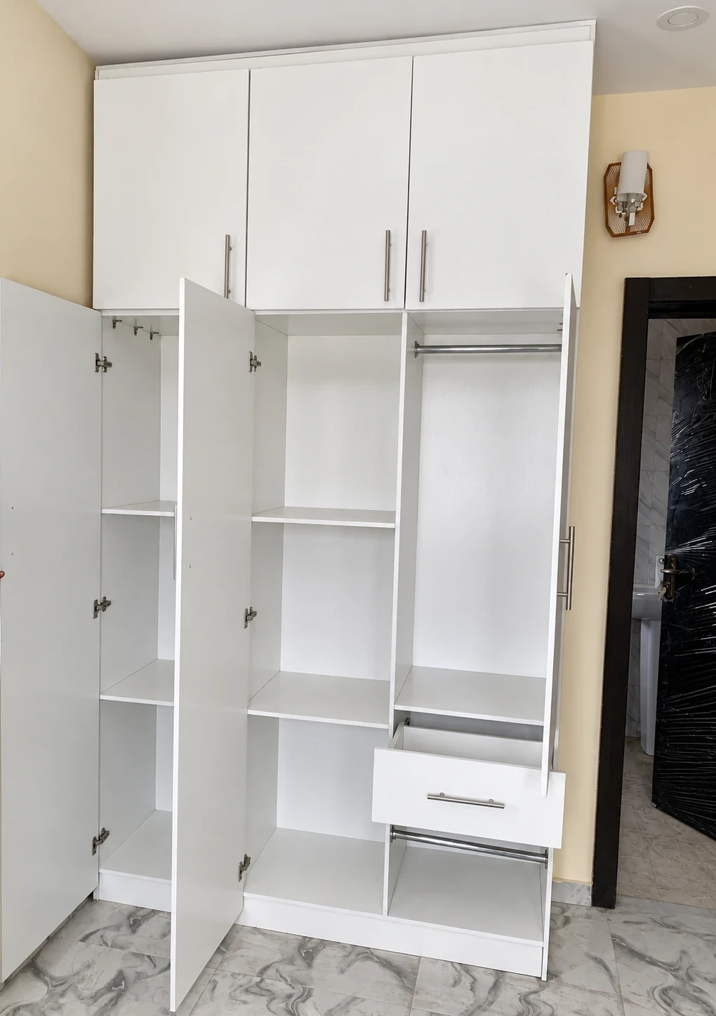 Open wardrobe showing shelves, hanging rails, a drawer and top cabinets